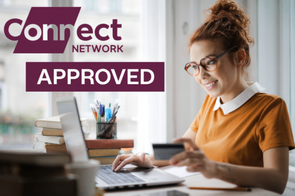 A woman with red hair tied in a bun is smiling while sitting at a desk, using a laptop and holding a credit card. She is wearing glasses and an orange top. On the desk are books and a pen holder with stationery. In the top left corner, there is branding that reads “Connect Network” and a banner that says “APPROVED.” This represents FCA-Regulated Mortgage Brokers