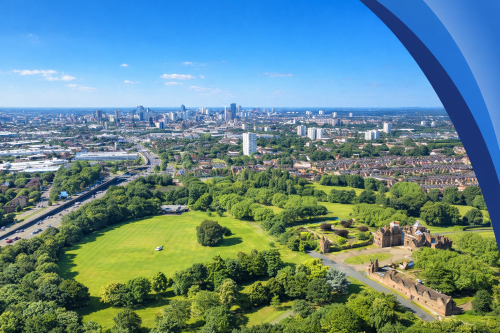 High resolution aerial view of a large green park with trees and historic ruins in the foreground, leading into a dense urban skyline under a bright blue sky. A curved blue branded design element frames the right side of the image.
