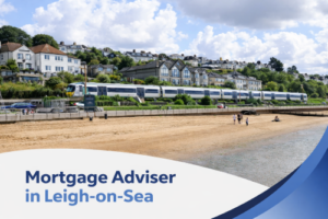 A bright daytime seaside scene in Leigh-on-Sea showing a sandy beach in the foreground, calm water at the shoreline, and a row of hillside houses behind a passing train. The image features the title “Mortgage Adviser in Leigh-on-Sea” with curved blue brand colour accents in the corner.