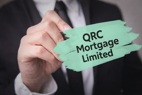 Close-up of a businessman in a dark suit holding a marker toward the camera. Over the image is a mint green brushstroke graphic displaying the text “QRC Mortgage Limited” in bold black letters.