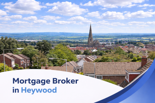 Mortgage broker in Heywood promotional banner featuring a bright summer view of the town with residential rooftops, a prominent church spire, rolling countryside in the distance, and realistic clouds in a blue sky, with a curved blue and white graphic overlay at the bottom.