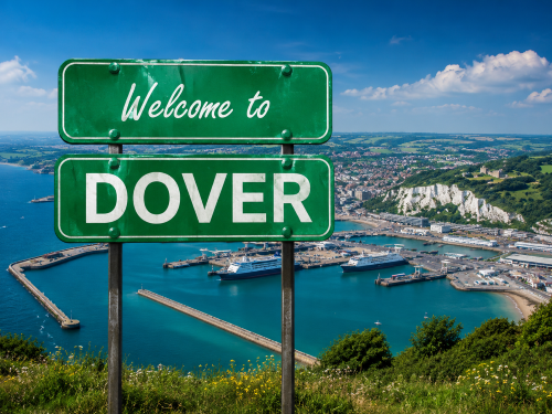 Welcome to Dover road sign overlooking Dover Harbour, the White Cliffs, ferry terminals, blue sea, and green coastal landscape. Why Move to Dover