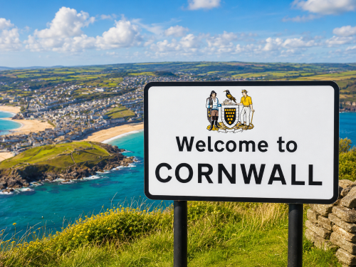 Welcome to Cornwall road sign overlooking a coastal town, sandy beaches, turquoise sea, cliffs, and green countryside. Why Move to Cornwall
