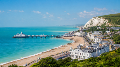 East Sussex coastline near Eastbourne, with a pier, seafront buildings, beach and chalk cliffs overlooking the sea.