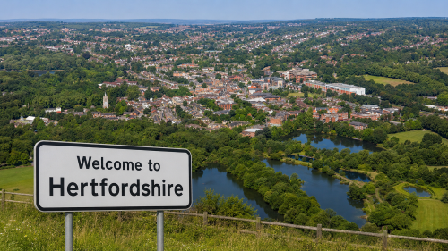 Why move to Hertfordshire, showing a Welcome to Hertfordshire road sign overlooking a green townscape, lakes, homes, and countryside.