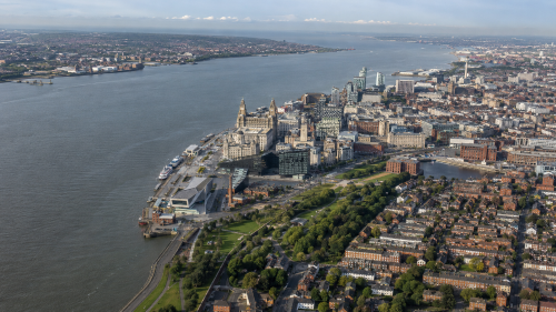 Wide aerial view of Liverpool and the River Mersey, showing the waterfront, green parks, residential areas, city buildings and the Wirral side of the river. Why Move to Merseyside