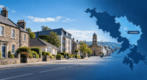 Mortgage Broker in Lockerbie hero image showing a quiet Lockerbie street with traditional and modern homes, a local civic landmark, and a branded Dumfriesshire map with a Lockerbie location pin.